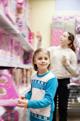 Two sisters in   children's toy store choosing doll.