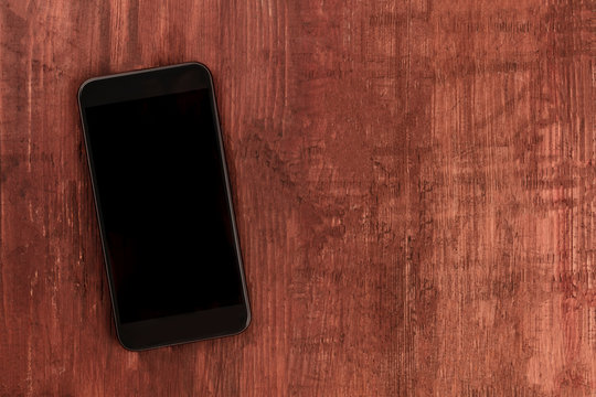 A smartphone, shot from the top on a dark wooden background, a mockup of a blank screen with copy space