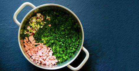 Traditional Russian summer cold soup okroshka with kefir in a saucepan on a dark background. View...