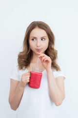 Beautiful happy young girl drinks organic berry, fruit smoothie on a white background.