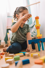 happy little girl playing with wooden blocks