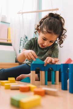 girl plays concentrated with building blocks