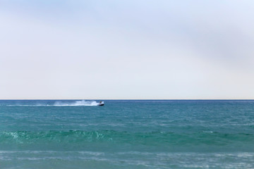 Fototapeta na wymiar Seascape with racing on the waves jet ski parallel to the horizon.