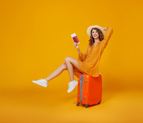 concept of travel. happy woman girl with suitcase and  passport on  yellow background
