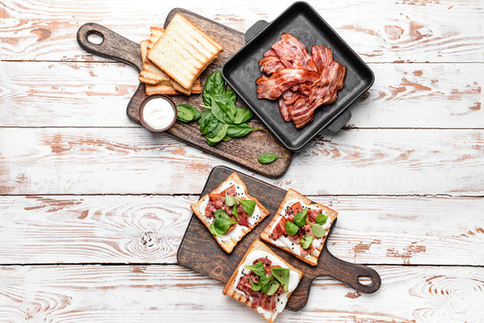 Tasty toasts with bacon on white table