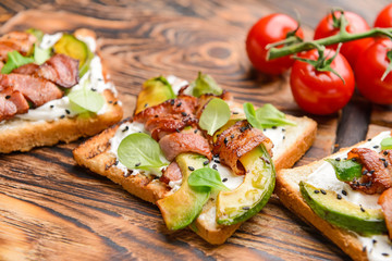 Tasty toasts with bacon on wooden board, closeup