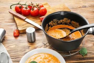 Saucepan with delicious cream soup on wooden table
