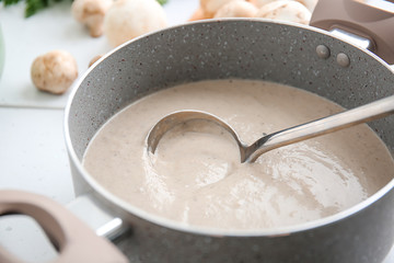 Pot with delicious cream soup on table, closeup