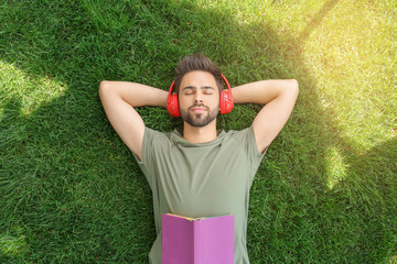Young man listening to audiobook in park, top view