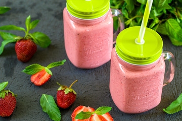 Freshly prepared fruit and milk summer cocktail of ripe berries. Refreshing strawberry mint smoothie with ice cream on wooden background. Soft diet drinks for a healthy lifestyle.