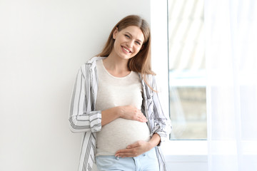 Beautiful pregnant woman near window