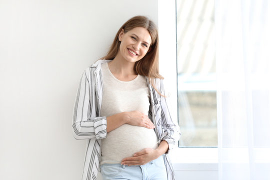 Beautiful pregnant woman near window