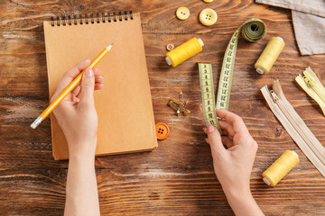 Female hands with notebook and accessories on wooden background