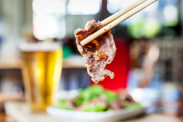 Close up of wood chopsticks clamp Boiled Beef dip with hot and lift up on blurred view of restaurant , Thai food style , Scald thin slices of beef in boiling water; instant-boil in Thai food style