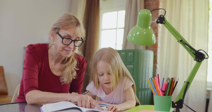 little blonde girl does homework with grandmother