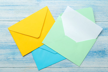 Multicolored envelopes with a blank for the text on a blue wooden table. top view