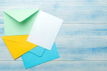 Multicolored envelopes with a blank for the text on a blue wooden table. top view