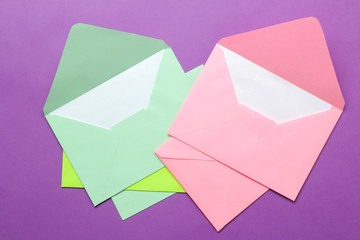 A multi-colored envelope with a blank for an inscription on a bright trendy lilac background. top view