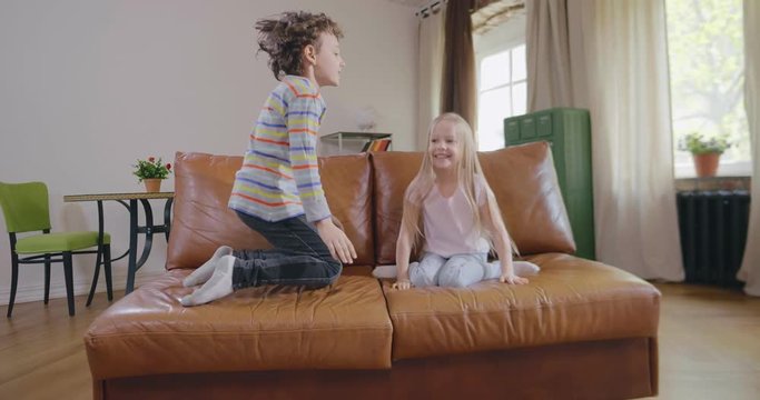 happy little boy and girl jump on couch
