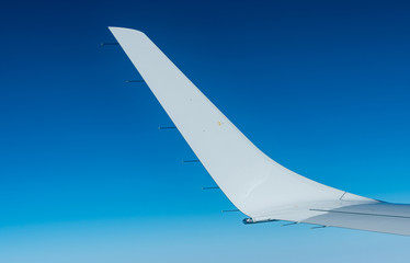 Wing of plane over white clouds. Airplane flying on clear blue sky. Scenic view from airplane window. Commercial airline flight. Plane wing above cloud. Flight mechanics concept. International flight.