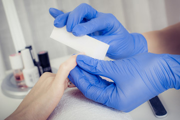 Woman receiving a manicure by a beautician with nail file