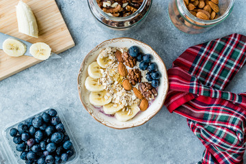 Acai Bowl with Yogurt, Blackberry, Banana Slices, Walnut, Honey, Jam, Oat, Almond, Sesame Seeds and Granola in Porcelain Bowl.