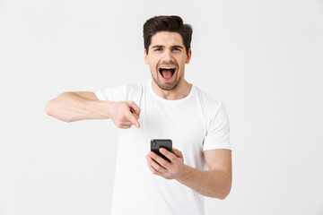 Excited happy young man posing isolated over white wall background using mobile phone.