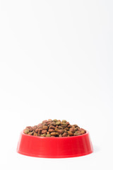 Red bowl with dry animal food for cats or dogs on white backgrou