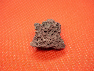 Geological specimen of natural red Pumice (pumicite, volcanic rock) on red background