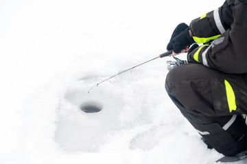 Winter fishing on ice. Man jiggling bait in an ice hole. Relaxin