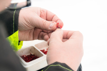 Man putting fishing bait on the hook. Winter fishing on ice. Rel