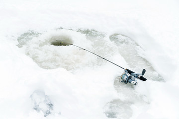 Winter fishing on ice. Jiggling bait in an ice hole. Relaxing in