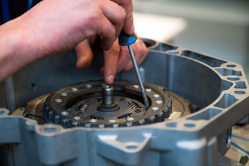 Repair man fixing car part with screw driver. Young mechanic at his workshop