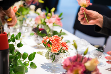 Closeup of hands of young woman florist creating bouquet of pink flowers on the table