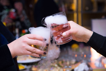 Beautiful couple holding dry ice cocktails at the party. Purple cocktail drink with ice vapor at the club, celebration