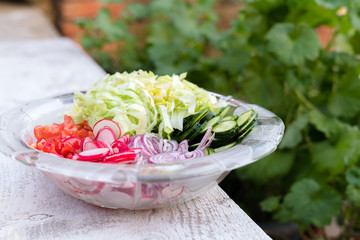 Freshly chopped summer salad. Many delicious vegetables in glass salad bowl - cucumber, lettuce, radish, tomatoes, red onion - Powered by Adobe