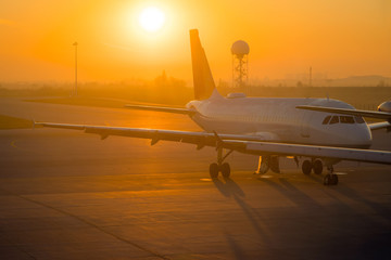 Fototapeta na wymiar Airplane about to take of from an air port. Aircraft wing at the airport, morning sunrise
