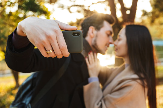 Beautiful loving couple posing walking outdoors in park nature take selfie by mobile phone.