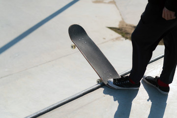 Young skateboard athlete standing on the ramp preparing to drop in on a skateboard. Practice freestyle, urban extreme sport activity for youth, staying out of trouble