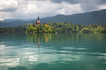 beautiful view on famous bled lake with church on island in stormy sky in julian alps, slovenia