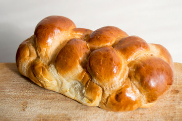 Fresh bread on wooden table. Bright shinned challah for Shabbat. Homemade challah bread, selective focus. Traditional bread.
