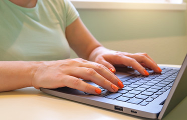 Close-up of woman's hands typing on laptop computer.