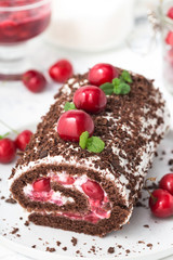 Chocolate roll cake with cream and cherries.