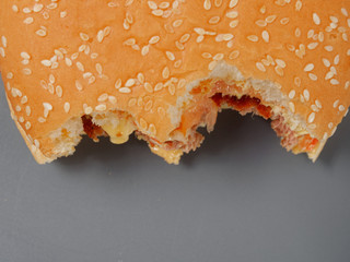 Obraz premium bitten big burger with cutlet cheese and tomato on a gray background