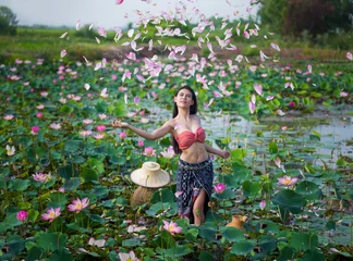 Fotobehang Lotusbloem Farmer woman, portrait beautiful model in local Thai costume and sombrero in the pink lotus blooming and falling field.  © Petch A Ratana