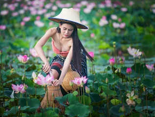 Foto op Canvas Farmer woman, portrait beautiful model in local Thai costume and sombrero catching fish in the pink lotus blooming field. © Petch A Ratana