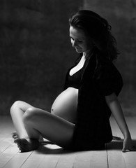 Fototapeta na wymiar Beautiful young pregnant happy mother woman posing on dark background