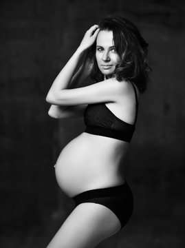 Beautiful young pregnant happy mother woman posing on dark background