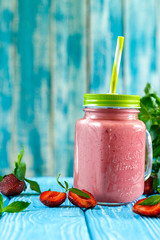 Freshly prepared fruit and milk summer cocktail of ripe berries. Refreshing strawberry mint smoothie with ice cream on wooden background. Soft diet drinks for a healthy lifestyle.