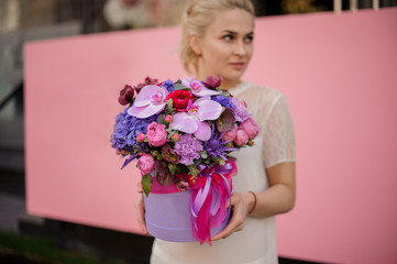 Blond girl holding bouquet in hat box with bow